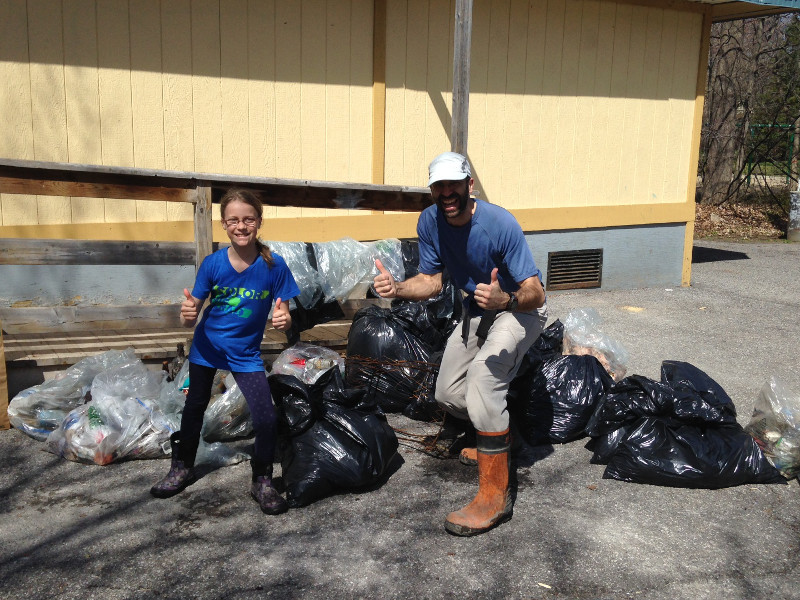 Deux bénévoles fiers de leur récolte posent devant les 20 sacs de déchets.